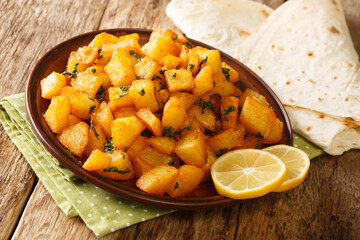 Batata Harra spicy potatoes a fairly popular Middle Eastern dish close up in the plate on the table. Horizontal