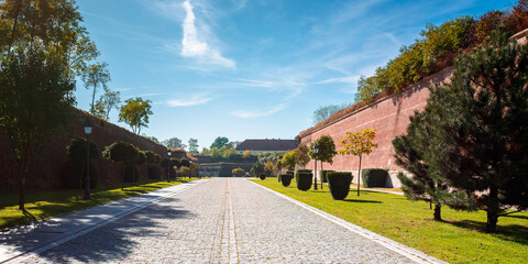 Fototapeta premium alba-iulia, romania - OCT 13, 2019: inner streets of alba carolina citadel in autumn. lanterns and benches by the walkway. huge walls around the path. popular travel destination