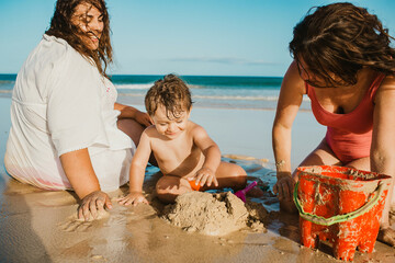 Mothers building sand castle with son on beach