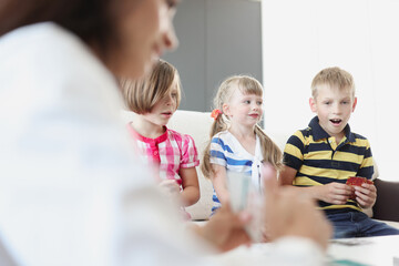 Group of children playing cards with an adult