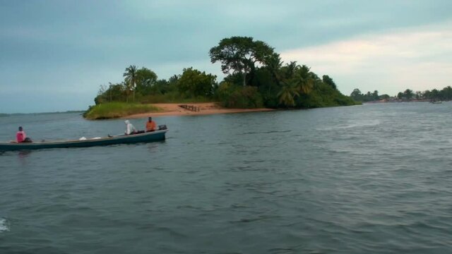 Motorized canoe boat passing by next to a small Island on lake Volta, Ada in Ghana, Africa