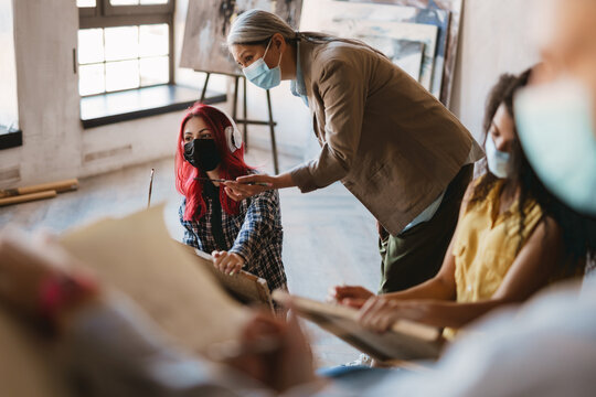 Mature Teacher Talking With Her Student During Class At Art School