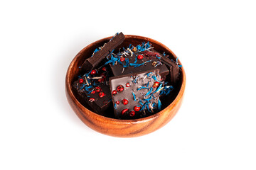 Dark chocolate with cherry, cranberry, pink pepper isolated on a white background. Chocolate pieces in wooden bowl.