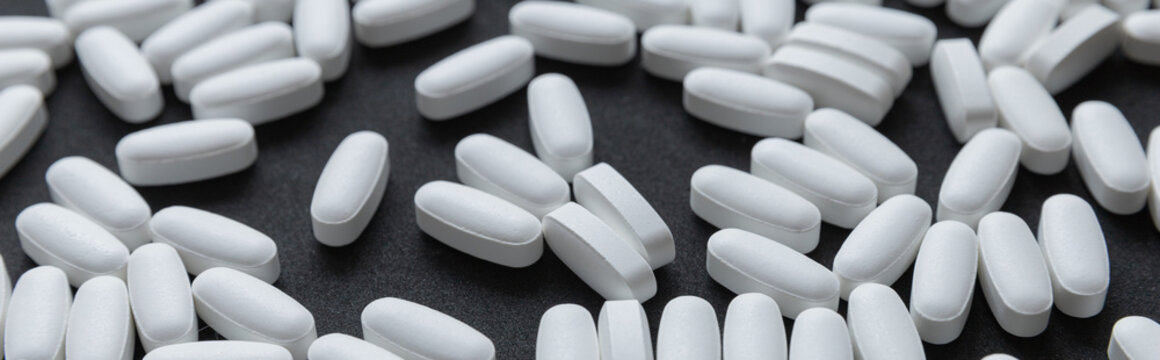 White tablets pills pattern over dark background