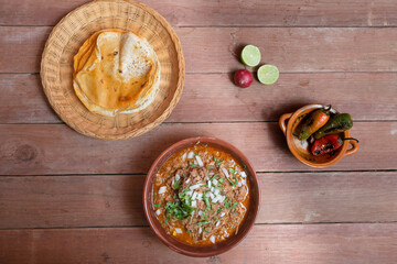 top view of birria with corn tortillas and roasted chili peppers. Mexican food