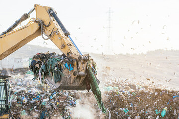 Excavator sorting metals for recycling at a recycling center, vertical image.
