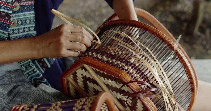 Cut in shot of Thai female farmer weave basket in traditional Thai art patterns to sell as extra income in countryside of Thailand.	