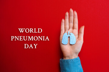 World pneumonia day. A woman's hand holds a cut-out silhouette of the lungs. Flat lay. Red background. Text