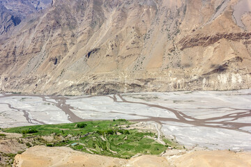 Aerial landscape view of the Spiti river and green fields of a Himalayan village in the mountains around Dhankar in Himachal Pradesh, India.