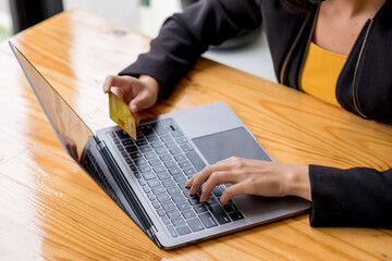 Business woman holding credit card and typing on the laptop for online shopping and payment makes a...