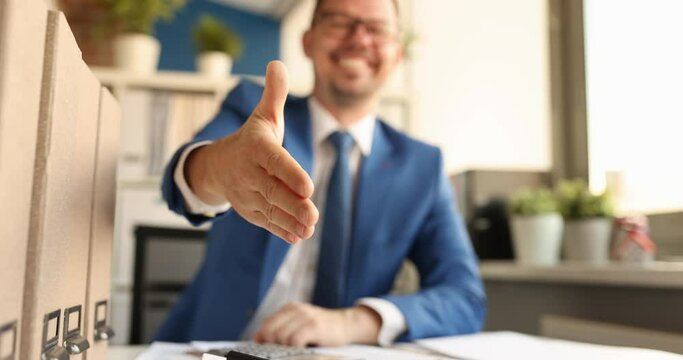 Young businessman sitting at table and stretching out his hand for handshake 4k movie