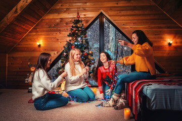 Christmas and new year. A group of young happy women socialize and untangle the lights. Scandinavian style interior