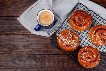 Traditional freshly baked Swedish cinnamon buns Kanelbulle with cup of coffee, copy space, top view