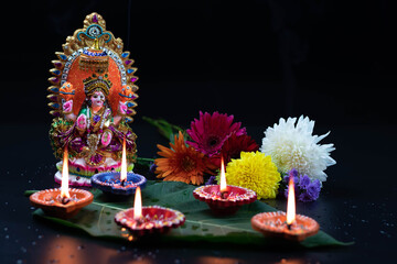 Handcrafted Eco Friendly Clay Murti Or Moorti Of Hindu Mata Lashmi Or Devi Laxmi Maa. Decorative Flowers And Diya Deep Dia Lit On Green Leaf. Theme For Diwali Pooja, Deepawali Puja Or Shubh Deepavali