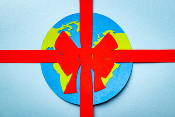 Papercut concept of Earth packed as a gift with the red ribbon