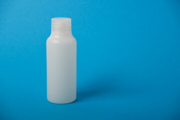 The concept of beauty salon and summer cosmetic White bottle for cosmetics on a blue background. Empty white plastic bottle