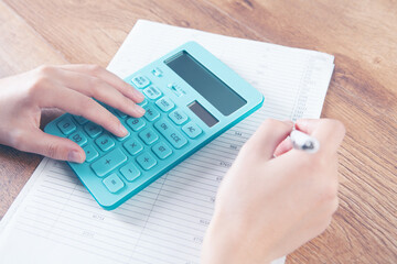 young woman counts on calculator and makes notes on papers