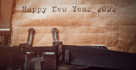 vintage typewriter with a brown sheet of paper and "Happy new year 2022" written on it.