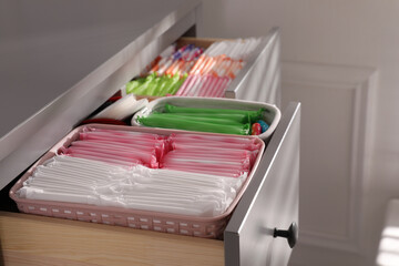 Open cabinet drawers with menstrual pads, tampons and pantyliners indoors, closeup