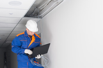 a master in a blue uniform, laid the wiring for the Wi-Fi router in a hidden false ceiling system...