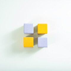 The adove view on four wooden cubes in two trend colors, yellow and grey, on the light background.