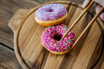 Kitchen utensils made of wood. Unusual photo. Bright pink doughnuts lying on a round wooden plate...