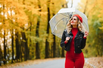 Woman under umbrella walks in the park in autumn