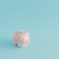 Creative arrangement made of pink piggy bank with cobweb on a blue background. Minimal savings concept. International savings day inspiration.