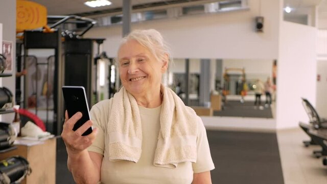 Portrait old woman in the gym. Physical culture for older people. Training and individual courses. Happy people smile, photographed on the phone, video call dances to music