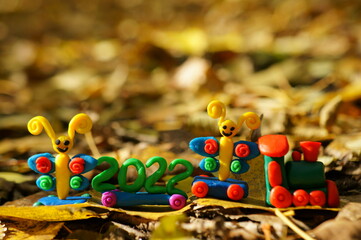 Fototapeta na wymiar A toy train with fairy-tale characters and the number 2022. Against the background of autumn leaves.