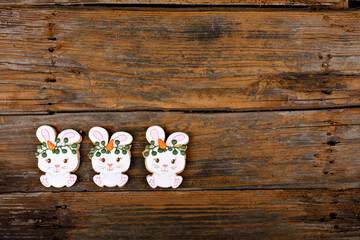 Closeup of variation of different Easter sugar cookies decorated with royal icing. Bunny rabbit with carrots on wooden background. Lovely sweet gift or postcard