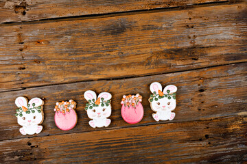 Fototapeta na wymiar Closeup of variation of different Easter sugar cookies decorated with royal icing. Bunny rabbit with carrots and eggs on wooden background. Lovely sweet gift or postcard