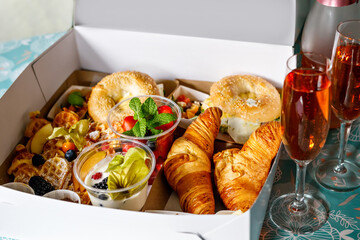 Breakfast in a box to go from closed restaurant due corona virus lockdown. Fresh bagels, croissants, berries, salad and vegetables for romantic lunch. Food to go for picnic.