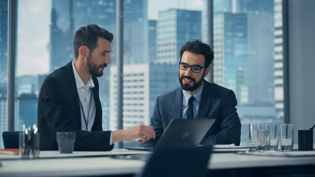 Businesspeople in Office: Business Meeting of Two Businessmen Using Laptop Computer and Talking. Tech CEO and Executive Director do Brainstorming for Digital e-Commerce Software Investment Solution