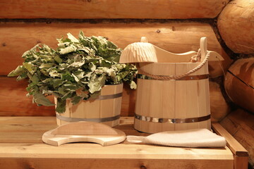 The still life with wooden buckets, oak broom and ladle in sauna interior.