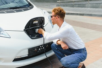 Smiling man unplugging the charger from the car