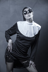 Naklejka na ściany i meble Beautiful woman wearing nun costume and halloween makeup over dark gray background