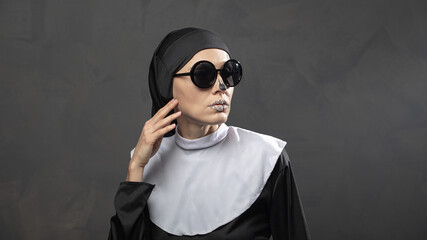 Beautiful woman wearing nun costume and halloween makeup over dark gray background