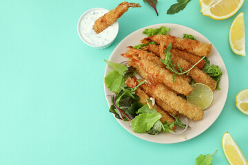 Сoncept of tasty food with deep-fried shrimp on mint background