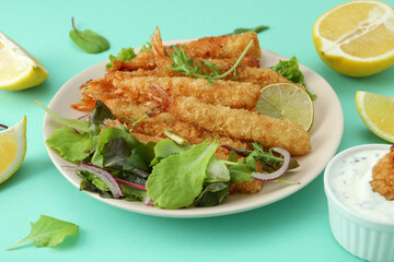 Сoncept of tasty food with deep-fried shrimp on mint background