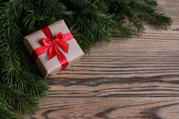 Fototapeta na wymiar Christmas gift and fir branches on a wooden background. Place for text. Boxing day concept