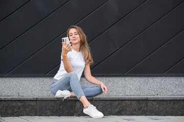 Happy and attractive blonde caucasian girl is using a smartphone.
