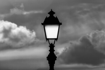 Fototapeta na wymiar Old fashioned street lamp against cloudy sky (Black and White)
