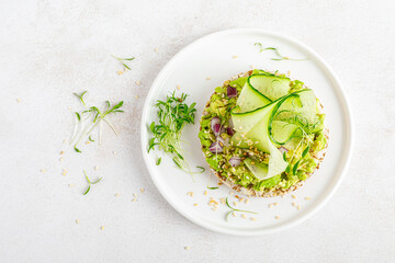Vegan open sandwich with dietary crispbread, fresh cucumber, onion, sesame seed, microgreens and avocado. Healthy vegetarian food, diet. Top view.