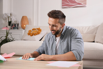 Happy man making paper plane at desk in living room