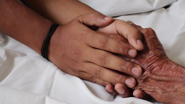 Worried man taking and gently stroking hand of  sick dad  showing care or love.