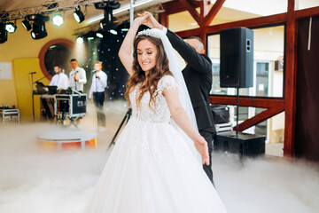The bride and her husband dance together their first wedding dance in the restaurant