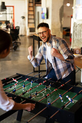 Colleagues having fun at work. Businessman and businesswoman playing table soccer..