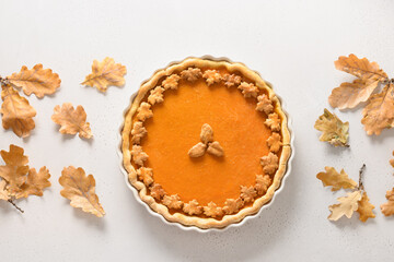 Homemade tasty Pumpkin Pie with autumn oak leaves for Thanksgiving Day on white background. View from above. Flat lay. Banner Fall.