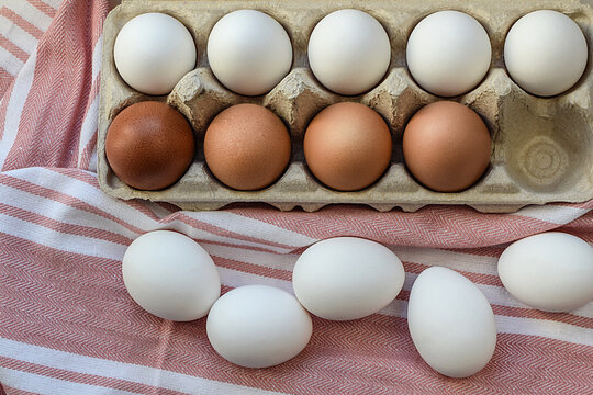 Chicken eggs in a cardboard box on a kitchen cotton napkin. Purchase and storage of eggs. Ingredient for Easter and healthy breakfast. Top view, flat lay. Selective focus.